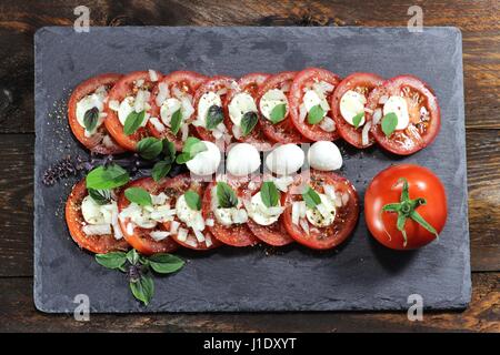 Tomate-Mozzarella auf Schiefer Stockfoto