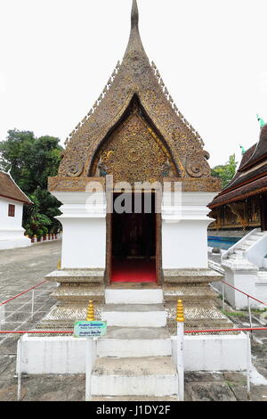 Buddha stehend, Kapelle-Giebel mit bunten Glasmosaiken Blumenmotiven und zwei Kinnaree-Dach Kreuzblumen mit Chofahs oder mythologischen Naga-Bronze ich Stockfoto