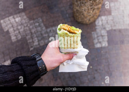 Mann hält Shawarma. Streetfood. Essen für unterwegs. Stockfoto