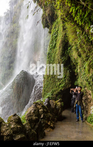 Provinz Guizhou, China.  Gelbe Frucht Baum (Huangguoshu) Wasserfall.  Touristen fotografieren hinter die Wasserfälle. Stockfoto