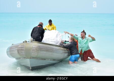 Hawaiian Staatsbedienstete Hebesack ein Müll in ein Boot wie Kunststoff und Meeresmüll angeschwemmt auf Kure-Atoll 26. März 2017 in Papahanaumokuakea Marine National Monument zu sammeln. Die NOAA Marine Debris Program entfernt Tausende von Pfund von verweigern jedes Jahr von den Inseln. Stockfoto