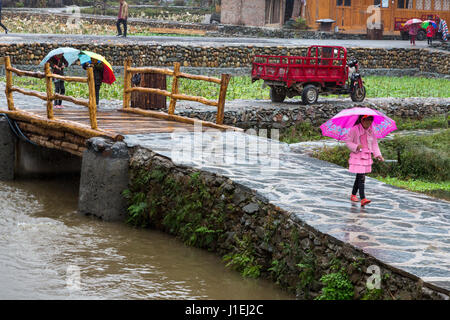 Huanggang, Guizhou, China.  Ein Dong ethnische Dorf.  Dong-Kinder im Regen nach Hause laufen. Stockfoto