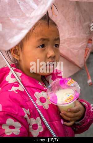 Huanggang, Guizhou, China.  Kleines Mädchen der ethnischen Gruppe der Dong, unter ihrem Dach. Stockfoto