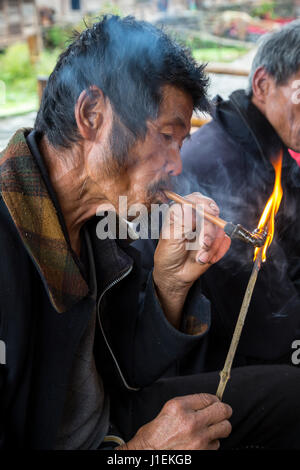 Huanggang, Guizhou, China.  Mann mittleren Alters der Dong ethnische Gruppe Beleuchtung seiner Pfeife. Stockfoto