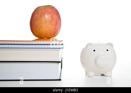 Ein Schuss des Apfels auf Bücher und ein Sparschwein für Bildungskonzept einsetzbar Stockfoto