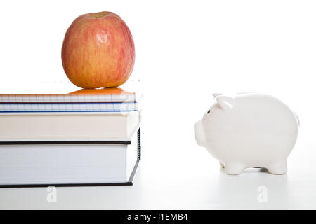 Ein Schuss des Apfels auf Bücher und ein Sparschwein für Bildungskonzept einsetzbar Stockfoto