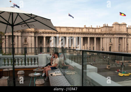 Gönnern an eine Rooftop bar mit Blick auf die viktorianischen Parlaments zur Spring Street, Melbourne, Australien Stockfoto