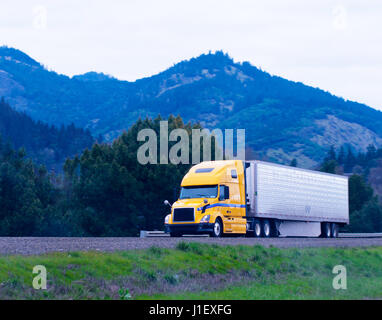 Moderne populäre leistungsstarke gelb groß rig Sattelschlepper mit einem Kühlschrank Anhänger Transporte Tiefkühlprodukte aus Kalifornien, Oregon durch die Straße Stockfoto