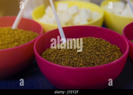 Löslicher Kaffee in einen rosa Teller und Zucker verfeinert in ein gelbes Schild auf blauem Hintergrund Stockfoto