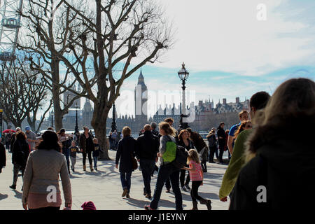 Big Ben im Hintergrund sichtbar als Menschenmassen entlang South Bank in London auf einer sonnigen, aber kalten Frühling - blauer Himmel und Wolken zu Fuß Stockfoto