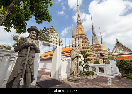 Zwei große chinesische Statuen, Bäume, Tor und Chedis in der Tempelanlage Wat Pho (Po) in Bangkok, Thailand. Stockfoto