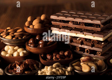 Verschiedenen Nüssen in Schalen auf Holztisch. Schokolade. Stockfoto