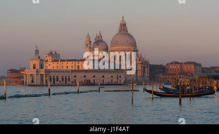 Gondeln festgemacht entlang der Riva Degli Schiavoni Waterfront mit Kirche von Santa Maria della Salute im Hintergrund Stockfoto