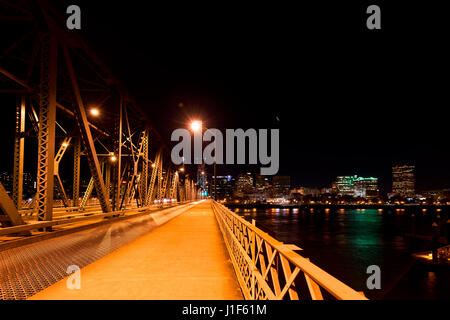 Orange Night light Fahrzeug- und Fußgänger-Brücke über den Willamette River in Portland mit leuchtenden Lichter auf dem Hintergrund beleuchtet Stockfoto