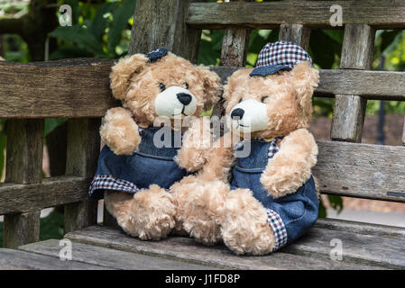 Zwei Teddybären sitzend auf Bank im Garten, Liebe und Freundschaft-Konzept Stockfoto