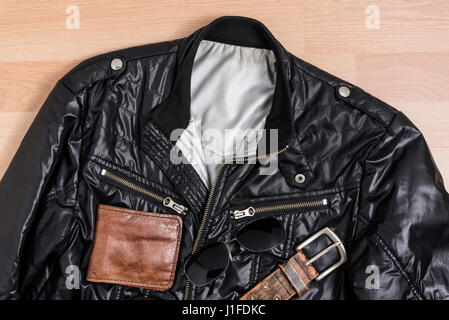 Lässige trendige Herrenmode mit schwarzer Jacke und Zubehör auf Holztisch Stillleben Stil Stockfoto