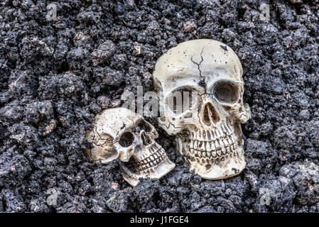 Zwei menschlichen Schädel, die halb begraben im Boden, gruseligen Horror-Konzept Stockfoto