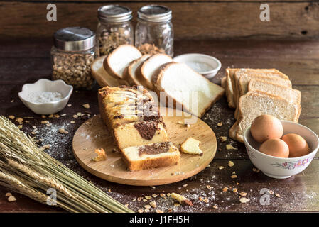 Marmor-Schokoladenkuchen auf Schneidebrett mit Brot und Zutat in der Küche Stockfoto