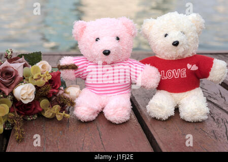 paar Teddybären Picknick im Garten mit Blumen am Fluss Hintergrund, Liebe Konzept Stockfoto