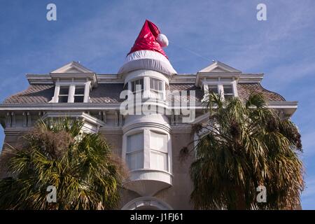 Eine riesige Weihnachtsmütze übertrifft das Dach von einem historischen Hause dekoriert zu Weihnachten am Meeting Street in Charleston, SC. Stockfoto