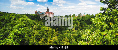 Zamek Ksiaz, eine Burg in Polen, gesehen von einem Aussichtspunkt mit einem Wald im Vordergrund. Stockfoto