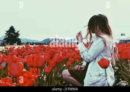 Mädchen sitzen im Bereich der roten Tulpen Stockfoto