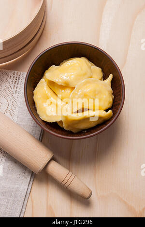 Frisch gekocht, hausgemachte ukrainische Teigtaschen mit Hüttenkäse oder Quark und Butter in Ton Schüssel auf hölzernen Hintergrund. Varenyky oder Knödel oder Piroggen ich Stockfoto