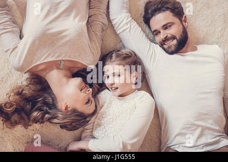 Draufsicht der glückliche Familie mit einem Kind zusammen auf Teppich liegend Stockfoto