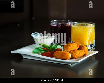 Kindermenü: knusprige Chicken Nuggets mit Tomaten, Basilikum und Sahne-Sauce auf einem weißen Teller Stockfoto