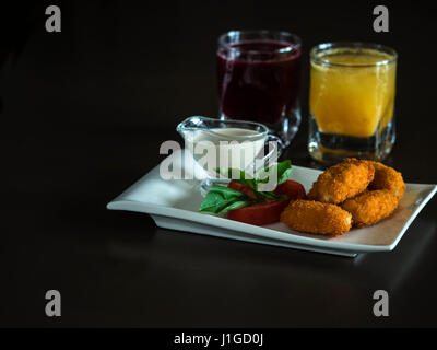 Kindermenü: knusprige Chicken Nuggets mit Tomaten, Basilikum und Sahne-Sauce auf einem weißen Teller Stockfoto