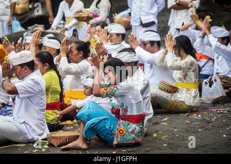 Masse der balinesische Hindu-Pilger beten in bunten Trachten auf Bali Strand in Tanah Lot Tempel mit Hände im Gebet Position bei einer Zeremonie Stockfoto