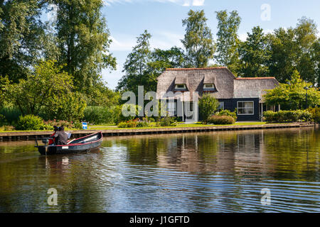 Blick auf kleinen Segelbooten in Kanälen um Bäume im landwirtschaftlichen Bereich. Giethoorn ist berühmte Dorf mit Thatcehd Dach Häuser. Stockfoto