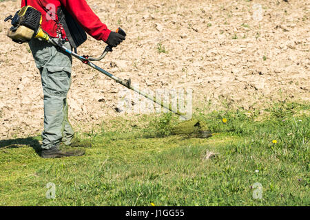 Männliche Arbeiter mit Power Tool String Trimmer Rasenmäher schneiden Rasengras im Garten Stockfoto