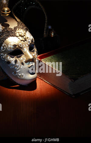 Vintage Stillleben. Schöne venezianische Maske in der Nähe von altes Buch Stockfoto