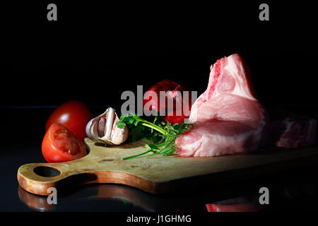 Frische Stück rohes Fleisch in der Nähe von Gemüse auf Holzbrett Stockfoto