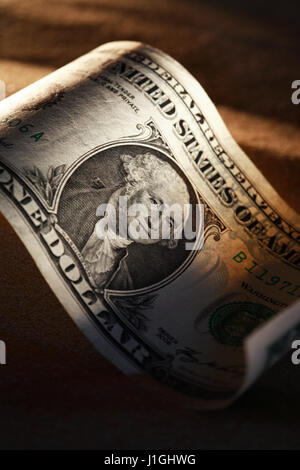 1 Dollar Banknote Closeup auf dunklem Sand mit Schatten Stockfoto