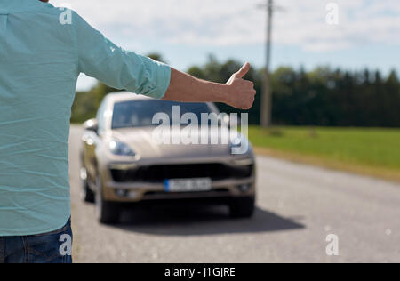 Mann, per Anhalter und Anhalten von Autos mit Daumen nach oben Stockfoto