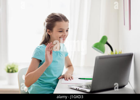 glückliches Mädchen mit Laptop zu Hause Hand winken Stockfoto