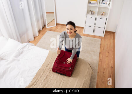 Frau Reisetasche und zeigt Daumen einpacken Stockfoto