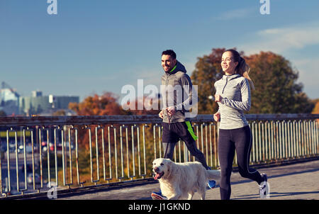 glückliches Paar mit Hund im freien laufen Stockfoto