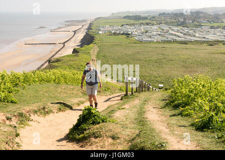 Eine Frau zu Fuß hinauf Beeston Hill oder Beeston Bump oder Beeston Buckel Norfolk UK an einem sonnigen Frühlingstag Stockfoto