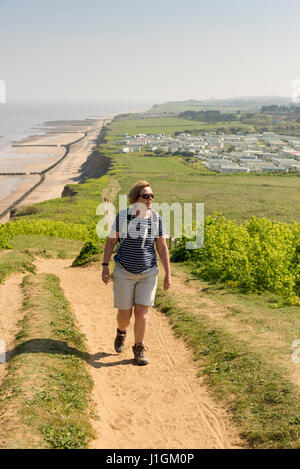 Eine Frau zu Fuß hinauf Beeston Hill oder Beeston Bump oder Beeston Buckel Norfolk UK an einem sonnigen Frühlingstag Stockfoto