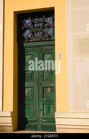 Grüne hölzerne Eingangstür auf einem gelben Fassade, Tirana, Albanien, Osteuropa. Stockfoto