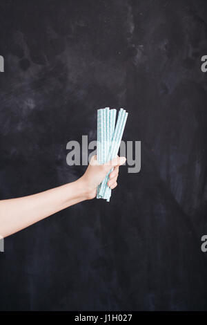 Frau Hand halten cocktail Stroh blau auf schwarzem Hintergrund. Stockfoto