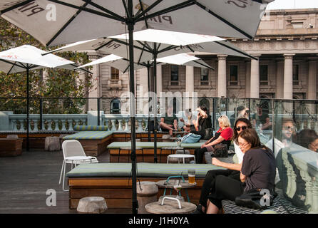 Gönnern an eine Rooftop bar mit Blick auf die viktorianischen Parlaments zur Spring Street, Melbourne, Australien Stockfoto