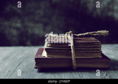 ein Haufen alter Bücher gebunden mit eine Jute string auf einem rustikalen Holztisch Stockfoto
