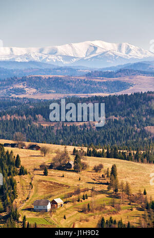 Schnee caped Berge im sonnigen Frühlingstag. Beskiden-Gebirge. Wald und Wiesen in einem Frühlingstal. Stockfoto