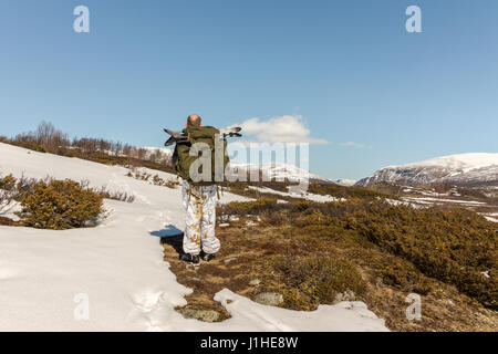 Mann mit großen Schneeschuhe in seinem Rucksack, Mann von hinten gesehen zu Fuß in Richtung der Berge in den Dovre-Nationalpark, Dovre Bergen in Norwegen Stockfoto