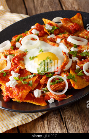 Mexikanisches Frühstück: Chilaquiles mit Ei und Huhn Nahaufnahme auf einer Platte. Vertikal Stockfoto