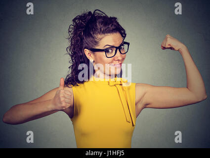 Junge glückliche Frau Muskeln zeigt Daumen hoch isoliert auf grauem Hintergrund. Positive Emotionen Gesichtsausdruck. Gewicht-Verlust-Wellness-Konzept Stockfoto